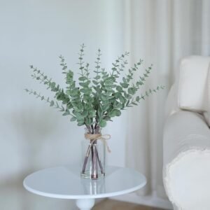 Add a touch of greenery with the VIERENA 17.5" Artificial Eucalyptus Stems in a glass vase, complete with faux water for a lifelike appearance. Featuring sage green leaves and white seeds, this elegant arrangement is perfect for centerpieces, farmhouse decor, weddings, or home accents. A unique flower vase that brings effortless charm and timeless style to any space.